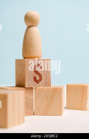 Figure en bois avec cubes sur un fond bleu. Concept d'un homme d'affaires prospère. Chemin vers le succès. Close up. La verticale. Banque D'Images