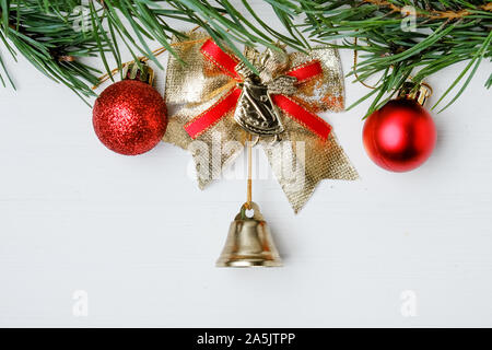 Golden Bell noël de l'arc, boules rouges et des branches de pins verts sur fond blanc. Banque D'Images