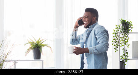 Young cheerful businessman talking on phone et holding Coffee cup Banque D'Images
