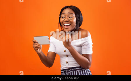 Excitée Black Girl Holding Smartphone Gesturing Oui, Studio Shot Banque D'Images