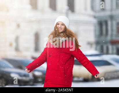 Femme rousse excité appréciant de neige tout en marchant par ville Banque D'Images