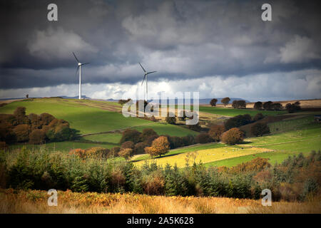 Les éoliennes situées sur la crête de la colline au-dessus de la vallée fertile avec ciel dramatique Banque D'Images