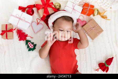 Adorable baby in Santa hat sieste avec cadeaux de Noël Banque D'Images