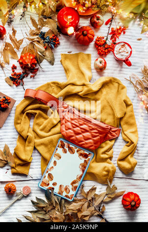 Comprimé jaune sur l'écran vide chandail tricoté avec orange taille ventre. Tasse de café avec une bougie, les citrouilles et les feuilles d'automne. Vêtements Mode d'automne. Banque D'Images