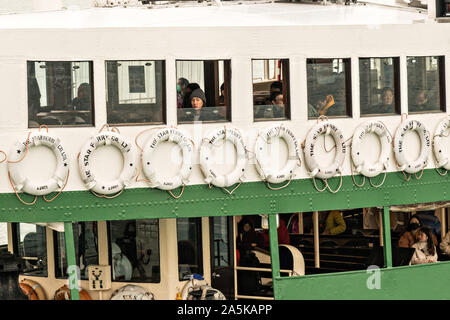 Les gens regarder par les fenêtres de l'embarcadère des ferries Star comme il traverse le port Victoria de Hong Kong. Star Ferry-boats ont été transporter des passagers de l'île de Hong Kong à Kowloon et retour depuis 1888. Banque D'Images