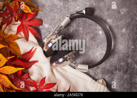 Casque confortable avec l'automne chaud et la musique de plaid tricoté sur le fond gris. Le mode de vie, l'automne, la musique concept. Banque D'Images
