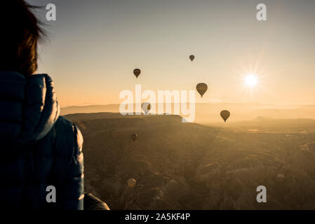 Woman enjoying view, des montgolfières en battant en arrière-plan, Göreme, Cappadoce, Nevsehir, Turquie Banque D'Images