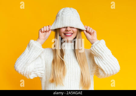 Smiling woman pulling down bonnet de laine blanche Banque D'Images