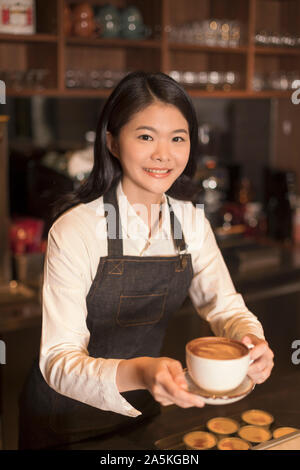 Barmaid debout derrière comptoir bar et holding Coffee cup Banque D'Images