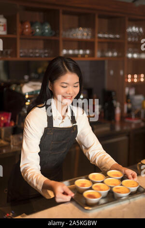 Barmaid debout derrière comptoir bar et holding tray Banque D'Images