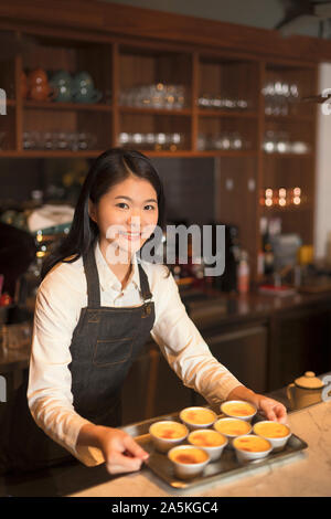 Barmaid debout derrière comptoir bar et holding tray Banque D'Images