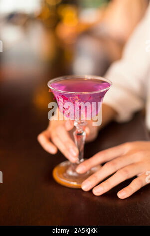 Close-up of woman's hands holding pink cocktail au comptoir du bar Banque D'Images