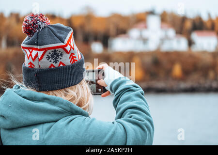 Femme photographe sur un bateau prend des photos avec son téléphone intelligent d'un phare de l'île de framboise, volontairement floues en arrière-plan. Banque D'Images