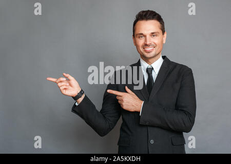 Studio affaires isolés sur gris pointant sur l'espace côté smiling happy Banque D'Images