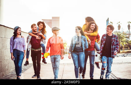 Groupe d'amis heureux de s'amuser en plein air - les jeunes sur le dos en riant et marcher ensemble dans le centre-ville Banque D'Images