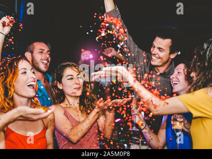 Happy friends faisant partie de jeter des confettis dans le Millénaire - club jeunes le plaisir de célébrer à la discothèque Banque D'Images