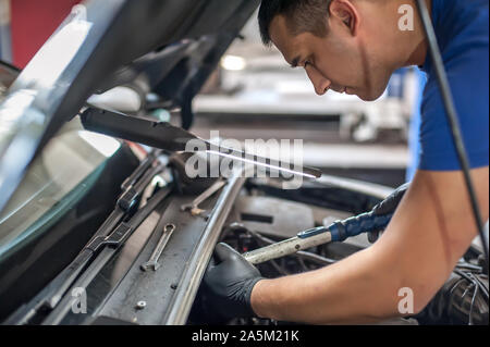 Maître mécanicien réparateur automobile auto service technicien vérifie et répare la condition du moteur sous le capot du véhicule service shop Banque D'Images