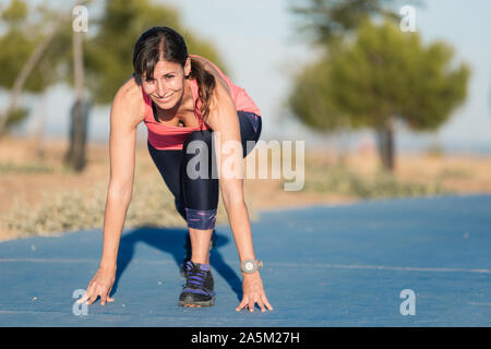 Femme athlétique sur une piste de course s'apprête à démarrer exécuter . Banque D'Images