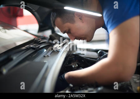 Maître mécanicien réparateur automobile auto service technicien vérifie et répare la condition du moteur sous le capot du véhicule service shop Banque D'Images