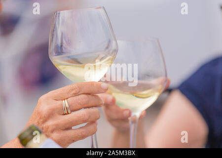 Photo détail de deux mains tenant deux verres de vin blanc. Concept de célébration. Banque D'Images