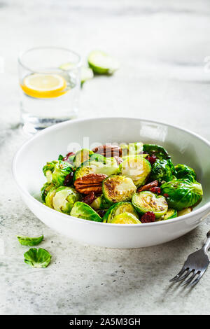 Salade de choux de Bruxelles rôtis avec les Canneberges et noix dans un bol blanc. La nourriture végétalienne saine concept. Banque D'Images