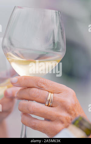 Photo détail de deux mains tenant deux verres de vin blanc. Concept de célébration. Banque D'Images