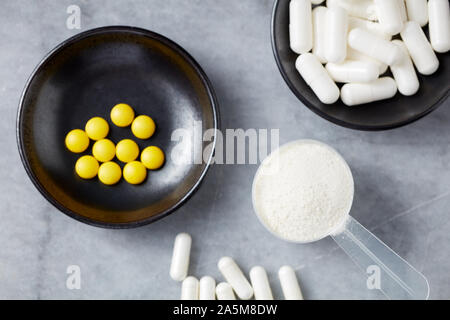 Poudre de collagène, Proline et MSM (soufre) et les capsules de vitamine C comprimés. Compléments alimentaires pour soutenir la production de collagène. Pierre lumineuse arrière-plan. Banque D'Images