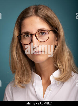 Portrait d'une femme blonde à lunettes en face de fond bleu Banque D'Images