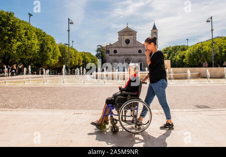 Femme mère poussant sur fauteuil roulant, la Piazza Risorgimento, Avezzano, Abruzzo, Italie Banque D'Images