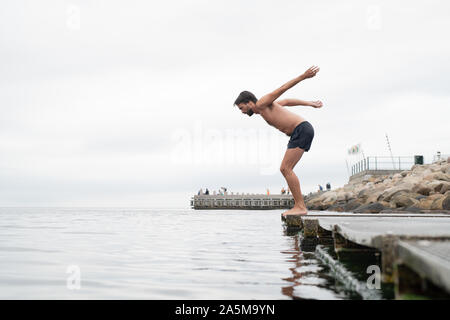L'homme de plonger dans la mer depuis boardwalk Banque D'Images