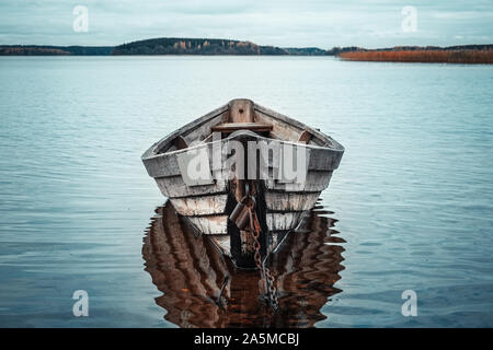 Bateau à rames en bois reflet dans un lac encore eau au crépuscule. Banque D'Images