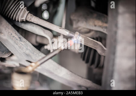 Location de maître mécanicien réparateur chauffage les vis avec le gaz butane chalumeau mini coup de lance-flammes du brûleur en service de réparation véhicule Banque D'Images