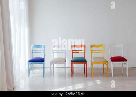 Chaises multicolores à l'intérieur d'une chambre blanche vide Banque D'Images