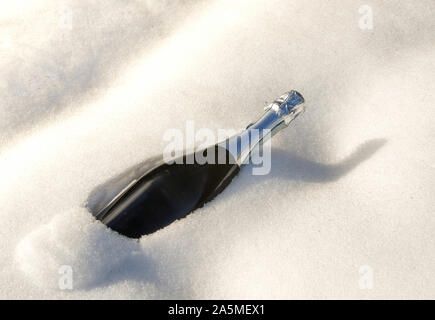 Non ouvert une bouteille de vin pétillant au frais dans un banc de neige en hiver Banque D'Images