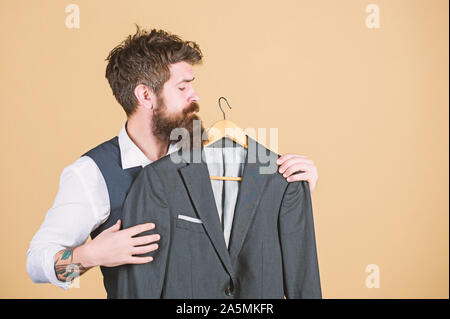 Lorsque l'invite officiellement dit. Homme barbu à l'usure formelle boutique. Le choix d'une veste de costume hippie dans une armoire. Classy formel regard de la mode Modèle. Banque D'Images