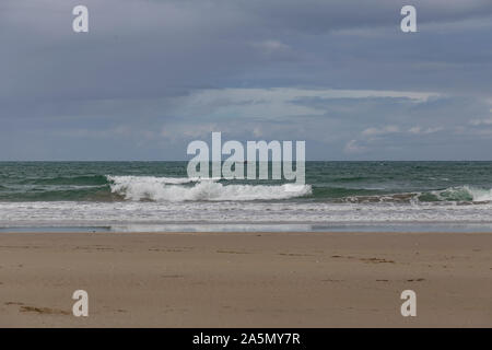 Petites vagues se brisant sur le sable blanc plage de Whangamata, péninsule de Coromandel. D'autres à l'autre est un petit voilier, yacht. Ciel bleu avec des nuages de tempête Banque D'Images