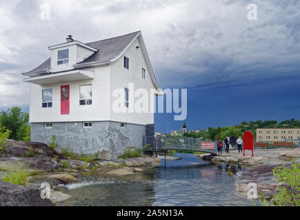 La fameuse petite maison blanche (La Petite Maison Blanche) au Saguenay qui a résisté à l'inondation de 1996, avec un ciel orageux au-delà Banque D'Images