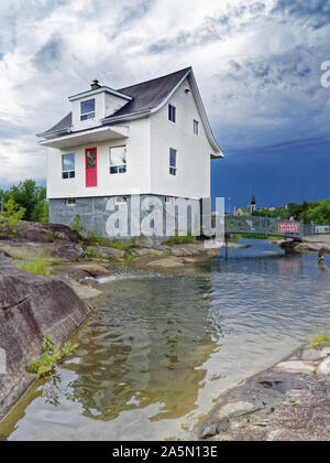 La fameuse petite maison blanche (La Petite Maison Blanche) au Saguenay qui a résisté à l'inondation de 1996, avec un ciel orageux au-delà Banque D'Images