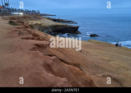 Une multitude de personnes, les touristes, y compris un couple, debout, marcher ou s'asseoir sur les falaises de la plage au coucher du soleil les falaises, San Diego, Californie Banque D'Images