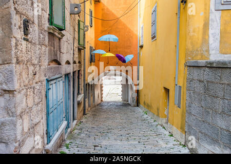 La Croatie, Istrie, vieille rue pavée, maisons traditionnelles et des parasols décorations dans la vieille ville historique de Labin Banque D'Images