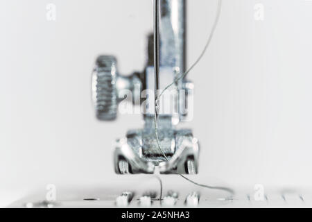 L'aiguille et le pied presseur de la machine à coudre comme un plan macro extrême, invention technique pour l'industrie du vêtement, l'arrière-plan lumineux avec copie espace, s Banque D'Images