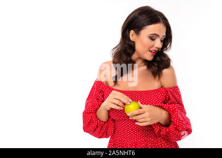 Jeune fille avec un ravissant sourire, dents blanche, rouge à lèvres rouge, de long cheveux châtains ondulés, beau maquillage, en robe rouge à pois vert avec stands Banque D'Images