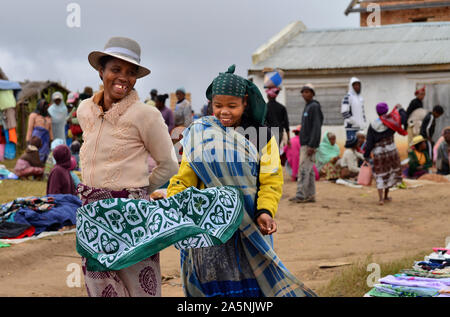 Deux femmes malgaches en souriant tout en vendant des vêtements dans un marché. Près d'Ambositra, Madagascar centrale Banque D'Images