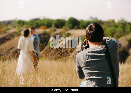 Photographe de mariage prend des photos de la mariée et le marié dans la nature en automne, le photographe en action Banque D'Images