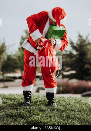 Stock photo du Père Noël sans barbe mettre permanent présente dans un sac rouge. Temps de Noël Banque D'Images