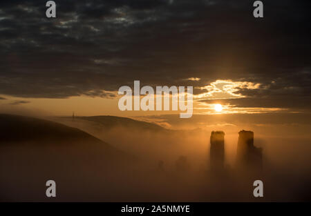 Le soleil se lève derrière un brouillard couverts Corfe Castle dans le Dorset. Banque D'Images