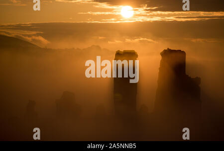 Le soleil se lève derrière un brouillard couverts Corfe Castle dans le Dorset. Banque D'Images