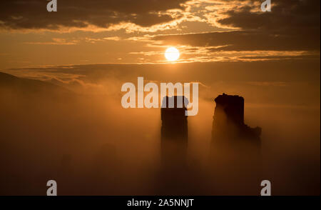 Le soleil se lève derrière un brouillard couverts Corfe Castle dans le Dorset. Banque D'Images