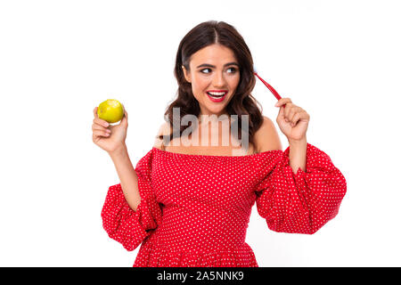 Jeune fille avec un ravissant sourire, dents blanche, rouge à lèvres rouge, de long cheveux châtains ondulés, beau maquillage, en robe rouge à pois vert avec stands Banque D'Images