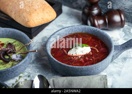 Les plaques gris avec des soupes différentes sur un fond gris. La plaque avec la Soupe aux asperges avec octopus, une assiette de bortsch traditionnel avec de la crème, une plaque Banque D'Images